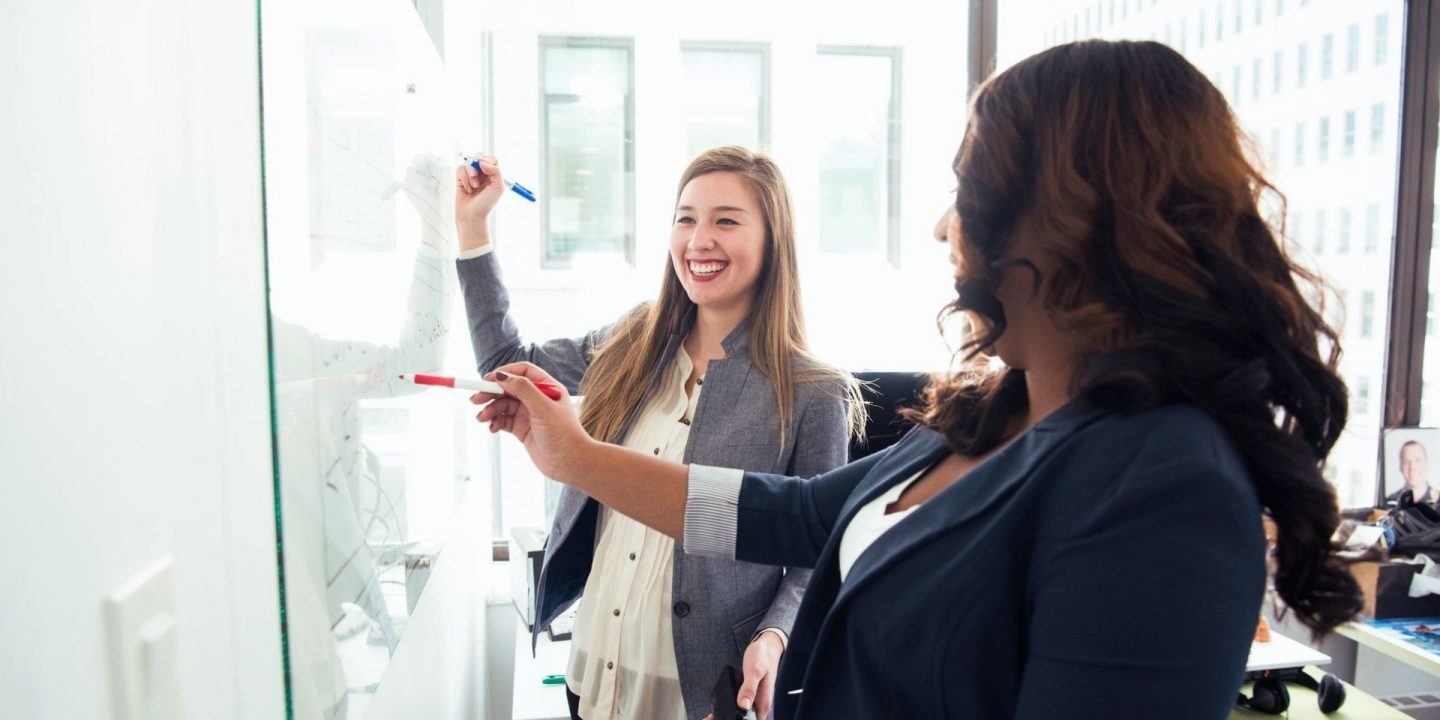 Two women in front of white board Two women in front of white board