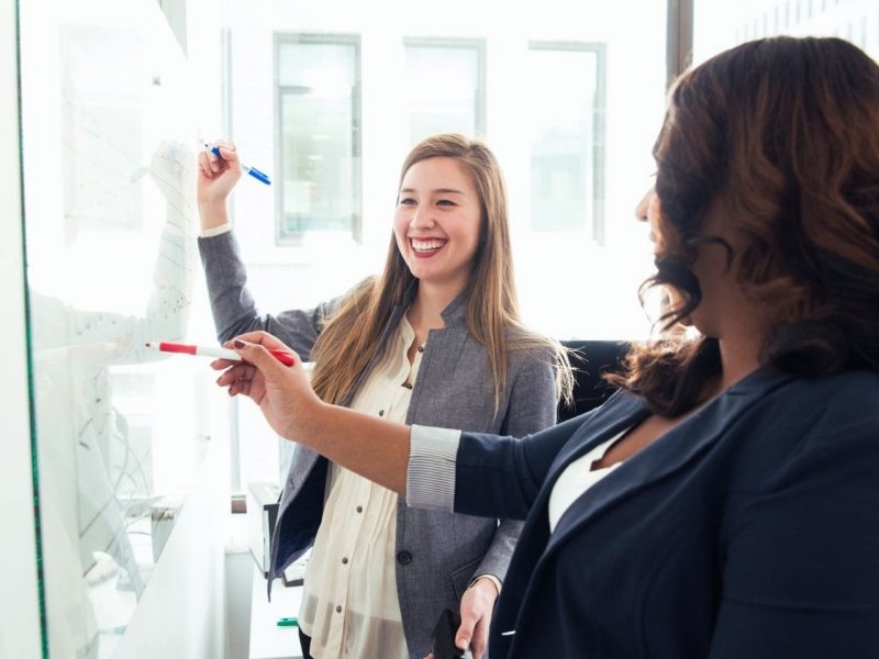 Two women in front of white board Two women in front of white board