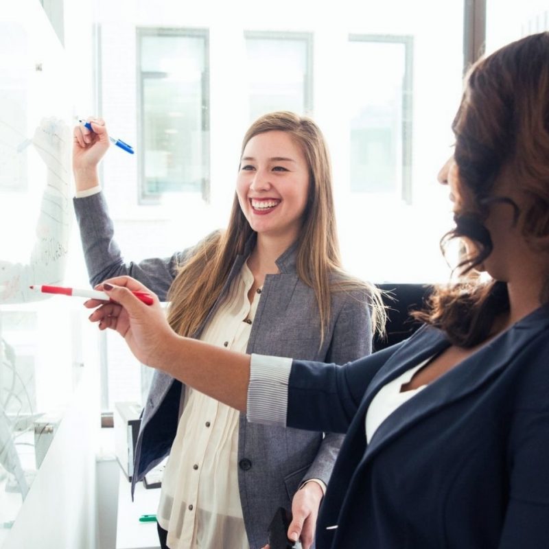 Two women in front of white board Two women in front of white board