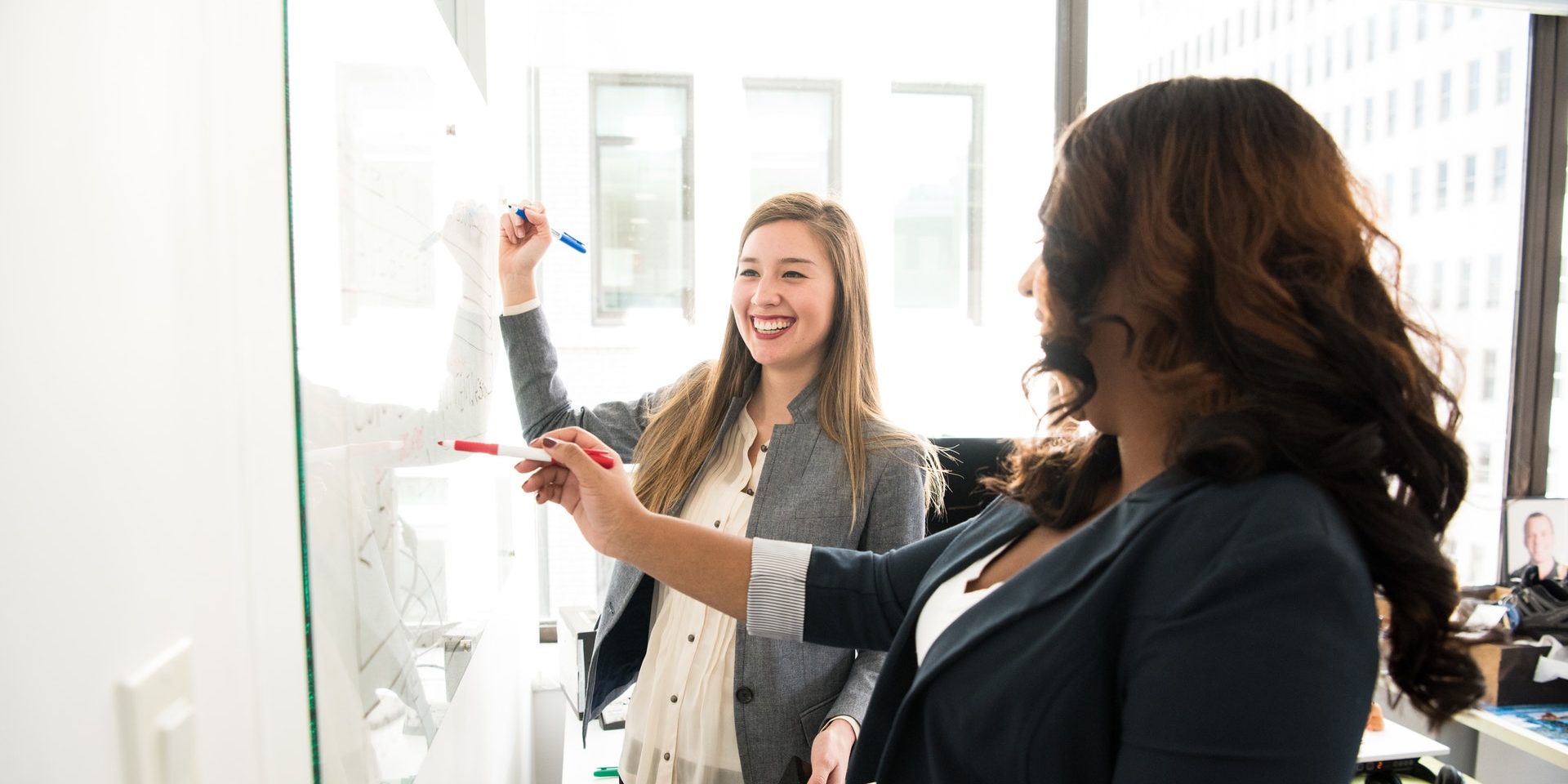two women in front of dry erase board two women in front of dry erase board